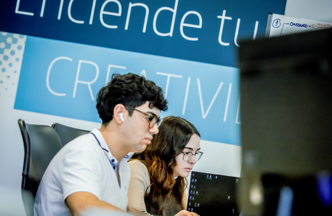 Plano medio de dos emprendedores jóvenes, un chico y una chica, trabajando en una oficina.